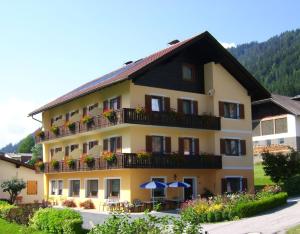 un grande edificio giallo con balconi, tavoli e ombrelloni di Haus Alpenfriede a Weissensee