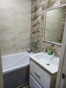 a bathroom with a sink and a tub and a mirror at ApartLux on Slavskogo 14 in Ustʼ-Kamenogorsk