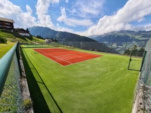 kort tenisowy z siecią na polu trawiastym w obiekcie Sporthotel Kalcherhof w mieście Racines