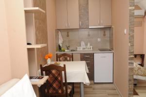 una pequeña cocina con mesa blanca y sillas en Favorit Apartments Čačak en Čačak