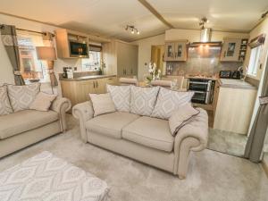 ein Wohnzimmer mit 2 Sofas und einer Küche in der Unterkunft Lancaster Lodge in Carnforth