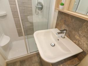 ein Badezimmer mit einem weißen Waschbecken und einer Dusche in der Unterkunft Lancaster Lodge in Carnforth + 14 Fotos