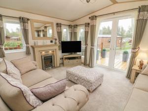 ein Wohnzimmer mit einem Sofa, einem TV und einem Kamin in der Unterkunft Lancaster Lodge in Carnforth