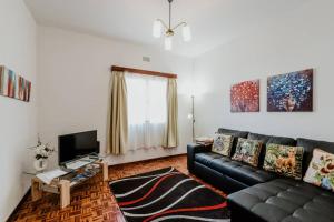 a living room with a black leather couch and a television at City View Gardens in Funchal