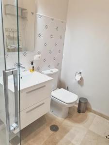 Baño blanco con aseo y lavamanos en Hispalis Casa Palacio Apartment, en Sevilla