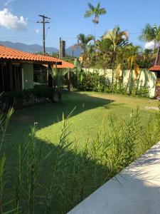 un patio con césped verde y una casa con palmeras en Casa linda c Piscina e WiFi na Praia de Camburi - SP, en São Sebastião