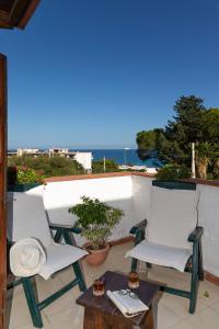 Dos sillas blancas y una mesa en un balcón. en Casa Pitea, en Mondello