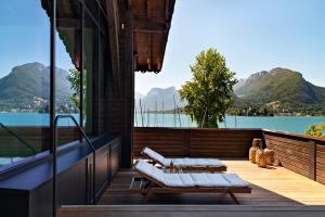 uma varanda com vista para a água e para as montanhas em Auberge Du Père Bise - Jean Sulpice em Talloires