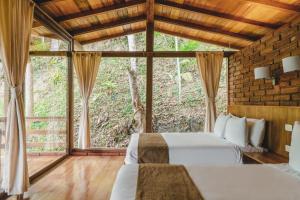 a bedroom with two beds and a large window at Piripe Wellness Lodge in Pacto
