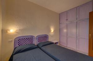 a bedroom with a purple bed and a closet at Baia de Bahas Residence in Golfo Aranci