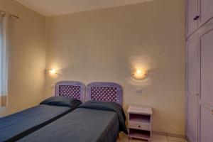 a bedroom with two beds and two lights on the wall at Baia de Bahas Residence in Golfo Aranci