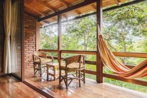 a room with a hammock and chairs on a porch at Piripe Wellness Lodge in Pacto