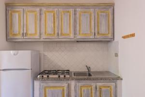 a kitchen with wooden cabinets and a white refrigerator at Baia de Bahas Residence in Golfo Aranci