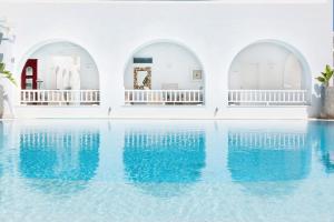 a pool with blue water in a white building at Stelia Mare Boutique Hotel in Naousa