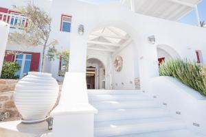 a white building with white stairs and vases at Stelia Mare Boutique Hotel in Naousa
