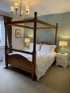 um quarto com uma cama de dossel em madeira com lençóis brancos em Three Tuns Ashwell em Ashwell