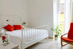 Dormitorio blanco con cama blanca y almohadas rojas en BORGHETTO STORICO - Fronte Castello, en Villar Dora