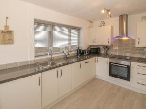 a kitchen with white cabinets and a sink at Seaside retreat in Porthmadog