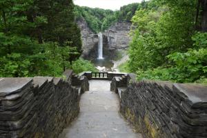 a waterfall in the middle of a stone wall with a pathway and a waterfall at Inn at Taughannock Falls in Ithaca