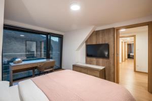 a bedroom with a bed and a desk and a television at Ubytovanie pod gaštanom in Hodruša