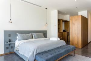 - une chambre avec un grand lit et un banc bleu dans l'établissement Suites BQ, à Guadalajara