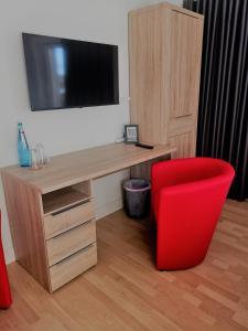 una silla roja junto a un escritorio con TV en Ferienwohnung Hofmeister, en Heilbad Heiligenstadt