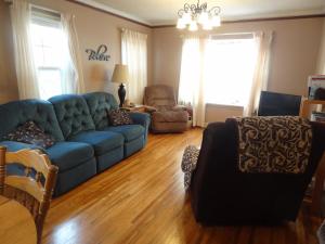 a living room with a blue couch and chairs at Covered By Faith Rentals -Storybook Home in Rochester