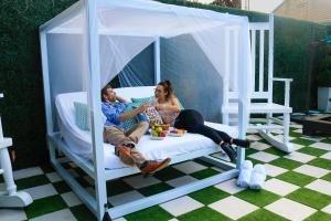 Un uomo e una donna seduti su un letto in un gazebo di 4 BR - Sleeps 8! Celebrity Villa Next to Frenchman St a New Orleans
