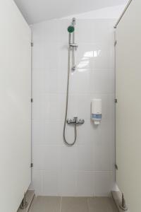 La salle de bains est pourvue d'une douche et de carrelage blanc. dans l'établissement Hostel Ghimbav Airport, à Ghimbav