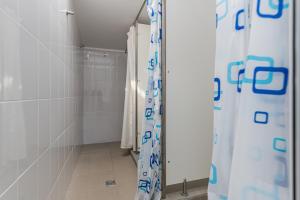 a walk in shower in a bathroom with white tiles at Hostel Ghimbav Airport in Ghimbav +26 photos