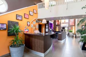 a restaurant with a bar in the middle of a building at Best Western Hotel Nuit De Retz Nantes Sud in Port-Saint-Père