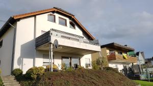 una casa blanca con un balcón en la cima de una colina en Wanderoase, en Melsbach