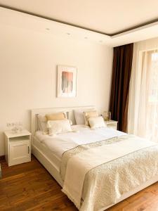 a white bedroom with a large bed and a window at Pirin Golf Studio Apartment in Razlog