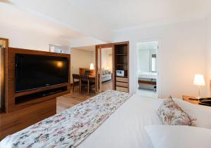 a bedroom with a large television and a bed at Hotel Nacional Inn Cambuí Campinas Residence in Campinas