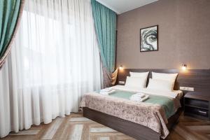 um quarto com uma cama e uma grande janela em Apart hotel Oblaka em Biysk