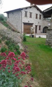 馬薩馬爾塔納的住宿－Umbrian Holiday on the enchanting hills of Todi!，一座花园,在一座建筑前方种有粉红色花卉