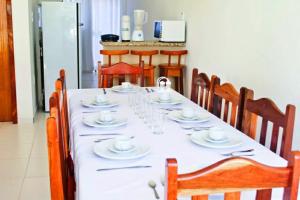 uma mesa longa com cadeiras e uma toalha de mesa branca em Residencial Monte Moria em Porto Seguro