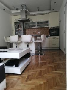 a kitchen with white chairs and a wooden floor at Ana Apartment in Novi Sad