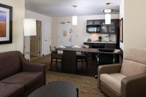 a living room with a table and chairs and a kitchen at Candlewood Suites Olathe by IHG in Olathe
