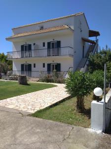 a large white house with a staircase in front of it at SAM'S ROOMS in Corfu
