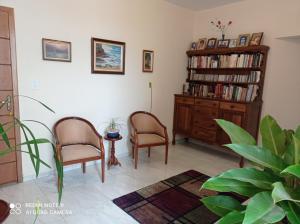 een woonkamer met 2 stoelen en een boekenplank bij Cunha centro - quarto cama de casal in Cunha