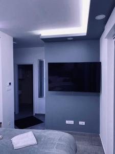 a bedroom with a blue wall with a flat screen tv at Jacuzzi Apartment Code 96 in Zagreb