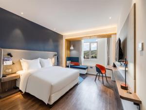 a hotel room with a white bed and a desk at Holiday Inn Express Litang by IHG in Lithang +83 photos
