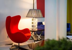 a red chair sitting next to a table with a lamp at Holiday Inn Express Lisboa - Av. Liberdade by IHG in Lisbon