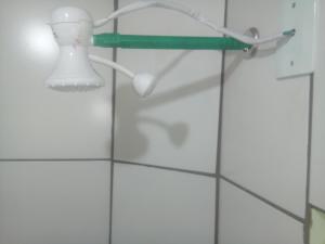 a white tiled bathroom with a light on a wall at Le Petit Chérie in Blumenau