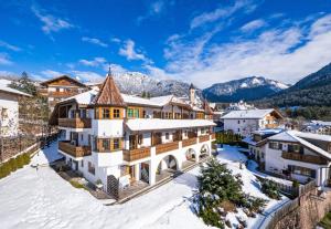 a house in the snow with mountains in the background at Residence Burghof in Siusi
