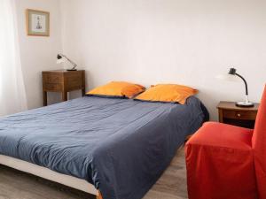 um quarto com uma cama com almofadas laranja e uma cadeira vermelha em Holiday home only 2km from Tr veneuc Beach em Saint-Quay-Portrieux