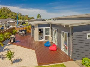 a house with a wooden deck next to a house at Modern Beach Pad - Whitianga Holiday Home in Whitianga
