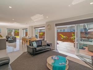 een woonkamer met een bank en een tafel bij Modern Beach Pad - Whitianga Holiday Home in Whitianga