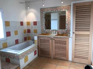 een badkamer met 2 wastafels, een bad en een spiegel bij Lush Holiday Home with Private Pool in Pougnadoresse